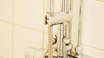 A chrome showerhead with a flexible hose attached to a wall-mounted faucet.