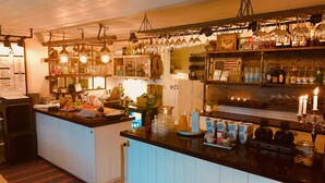 A bar area with shelves of bottles, glasses, and a sign with 'KÖ'.