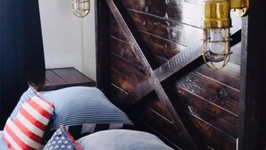A cozy room with a wooden accent wall, a hanging plant, and a shelf with books and decorative items.