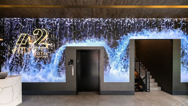 A hotel entrance with a digital waterfall display, a reception desk, and a staircase leading to the upper floor. - 42 Hotel (Brooklyn)