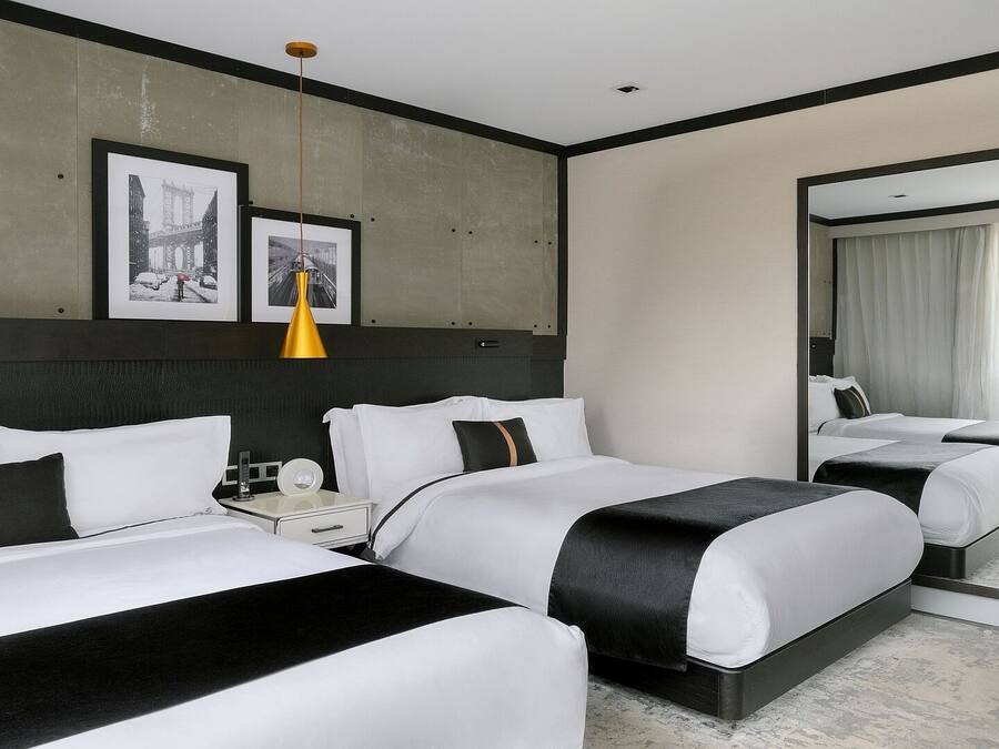 A hotel room with two beds, a large mirror, and artwork on the wall.