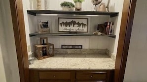 A compact kitchen with a built-in countertop, wooden cabinets, and a decorative sign above the sink. - 2118  The Owl Cove! Level entry - Hot tub, sauna & more resort amenities (Beech Mountain)