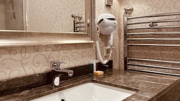 Un bagno con lavabo in marmo, portasciuga asciugamani, asciugacapelli e specchio.