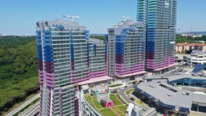A modern high-rise building with a unique architectural design featuring multiple balconies and a mix of glass and metal materials.