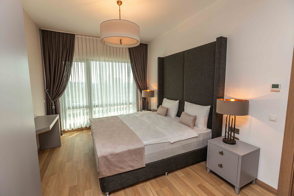 Une chambre à coucher moderne avec un grand lit, des tables de chevet et une petite table de nuit.
