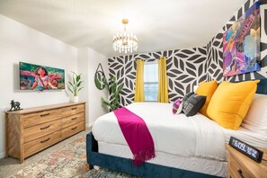 A bedroom with a bed, a nightstand, a dresser, a chandelier, and a wall with a leaf pattern. - Disney Getaway w/ Private Pool, Hot Tub & Game Room (Kissimmee)