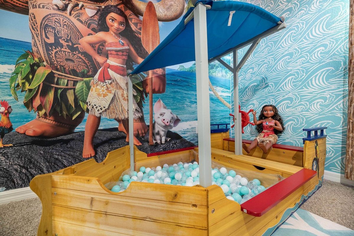 A play area with a wooden boat, a blue umbrella, and a mural of a tropical scene.