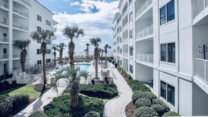 Un hotel moderno con varios balcones, una piscina y jardines bien cuidados.