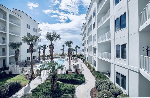 A modern hotel with multiple balconies, a swimming pool, and well-maintained landscaping.
