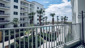 Un hotel de varios pisos con balcones, palmeras y vista al océano.