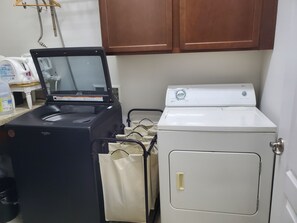 A laundry area with a black appliance, a white dryer, and a beige cabinet.