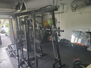 A gym with a squat rack, weight bench, and various exercise equipment.