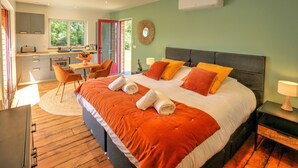 Een slaapkamer met een groot bed, een bureau en een stoel in een lichte kamer met uitzicht.