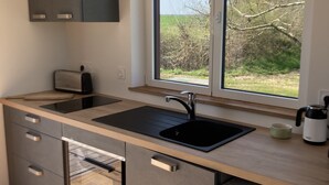 Een moderne keuken met een groot raam, inbouwapparatuur en uitzicht op de omgeving.