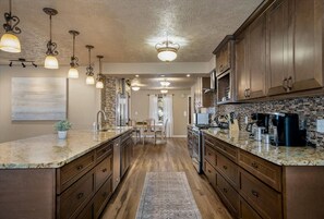 A kitchen with granite countertops, wooden cabinets, and a central island.