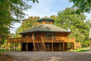 A wooden cabin with a balcony and a covered porch area.