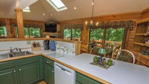 Une cuisine dotée de meubles en bois, d’un lave-vaisselle, d’un grand îlot central et offrant une vue sur l’extérieur.