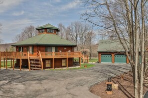 A log cabin with a balcony, a garage, and a bear statue.