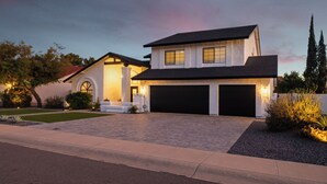 Une maison moderne à deux étages, dotée d’un garage, d’un éclairage extérieur soigné et d’une allée aménagée.