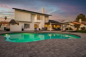 A modern house with a swimming pool, patio furniture, and a well-lit outdoor area.