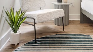 Een moderne slaapkamer met een stapelbed, een potplant, een ronde tafel met een vaas, en een raam met uitzicht op bomen en huizen.