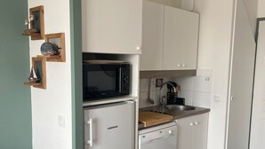 A compact kitchen with white cabinetry, a built-in microwave, a dishwasher, and a wooden countertop. - Port du Crouesty. duplex rénové, calme, terrasse, idéal en famille (6 pers) (Arzon)