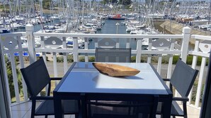 A balcony with a table and chairs overlooking a marina filled with boats. - Port du Crouesty. duplex rénové, calme, terrasse, idéal en famille (6 pers) (Arzon)