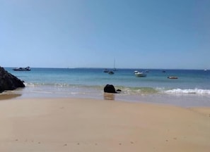 A beach with clear skies, calm waters, and boats.