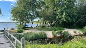 A wooden pier leading to a sandy beach with a small stream and dense trees. - Villa 3 bedrooms 900 m from Lac de Parentis (Parentis-en-Born)