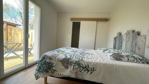 A bedroom with a bed, a sliding glass door leading to an outdoor area, and a wooden floor. - Villa 3 bedrooms 900 m from Lac de Parentis (Parentis-en-Born)