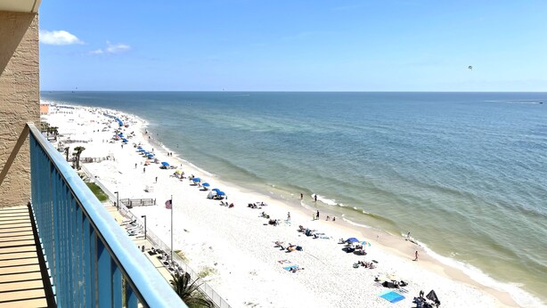A beach with a long stretch of sand, a few umbrellas, and a few people. - Surf Side Shores 1906 | 3 bd 3 ba | gulf-front  (Gulf Shores)