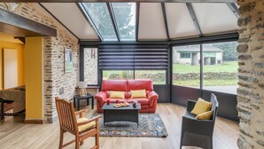 A cozy living area with a red sofa, a wicker chair, and a coffee table. - LA LONGERE DU TERTRE - Charmante longère proche plage (Cancale)