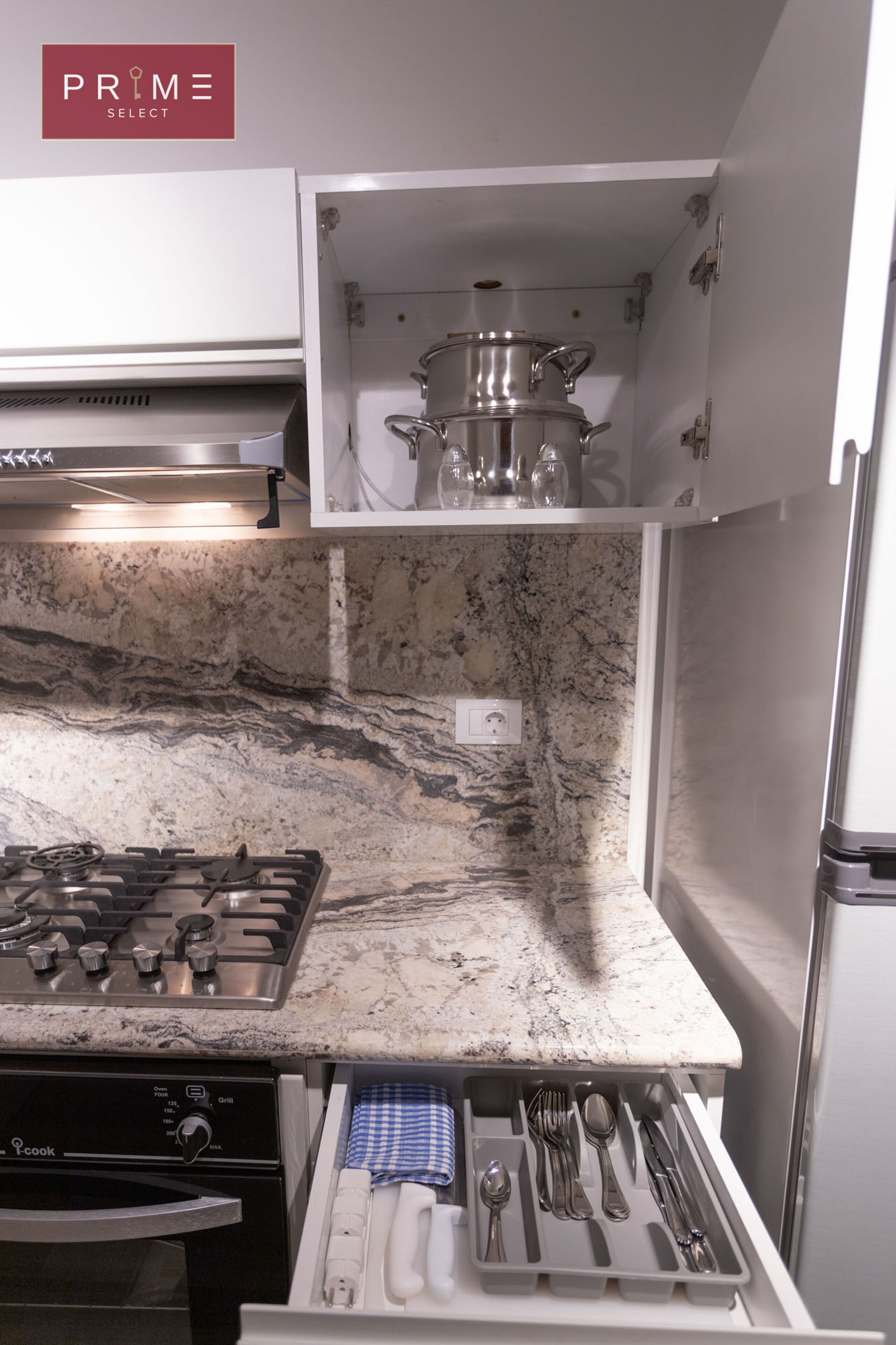 A kitchen with a gas stove, a built-in oven, a marble countertop, and a utensil drawer.