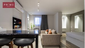 A modern hotel room with a dining area, a sofa, and a bed.