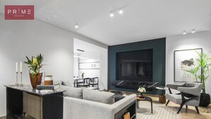 A modern living room with a sofa, coffee table, and a TV mounted on the wall.