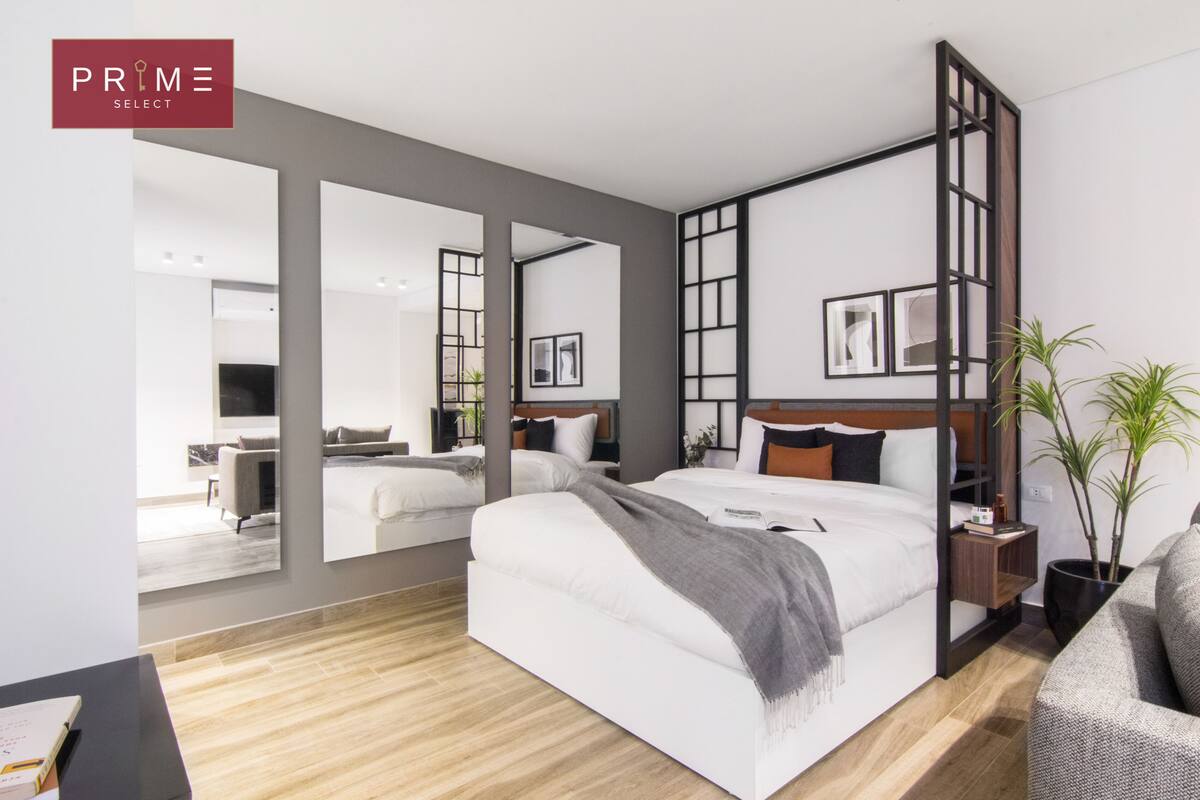 Una habitación de hotel moderna con una cama grande, un escritorio y una zona de estar.