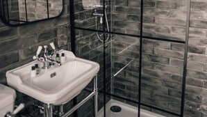 A bathroom with a white sink, a mirror, and a shower area with a glass door. - Kirkwall Hotel (Kirkwall)