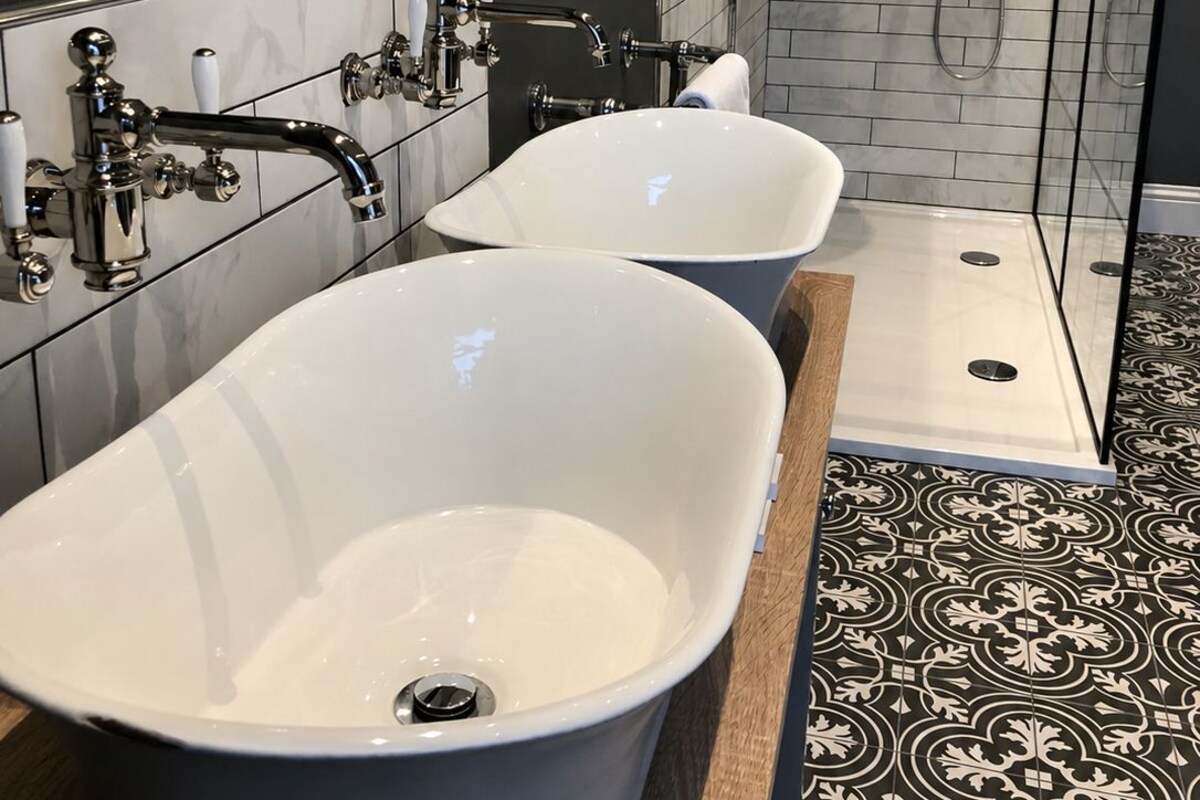 A bathroom with two freestanding tubs, a shower enclosure, and a tiled floor.
