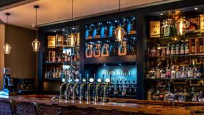 A bar area with a marble table, leather chairs, and a variety of liquor bottles on shelves. - Kirkwall Hotel (Kirkwall)