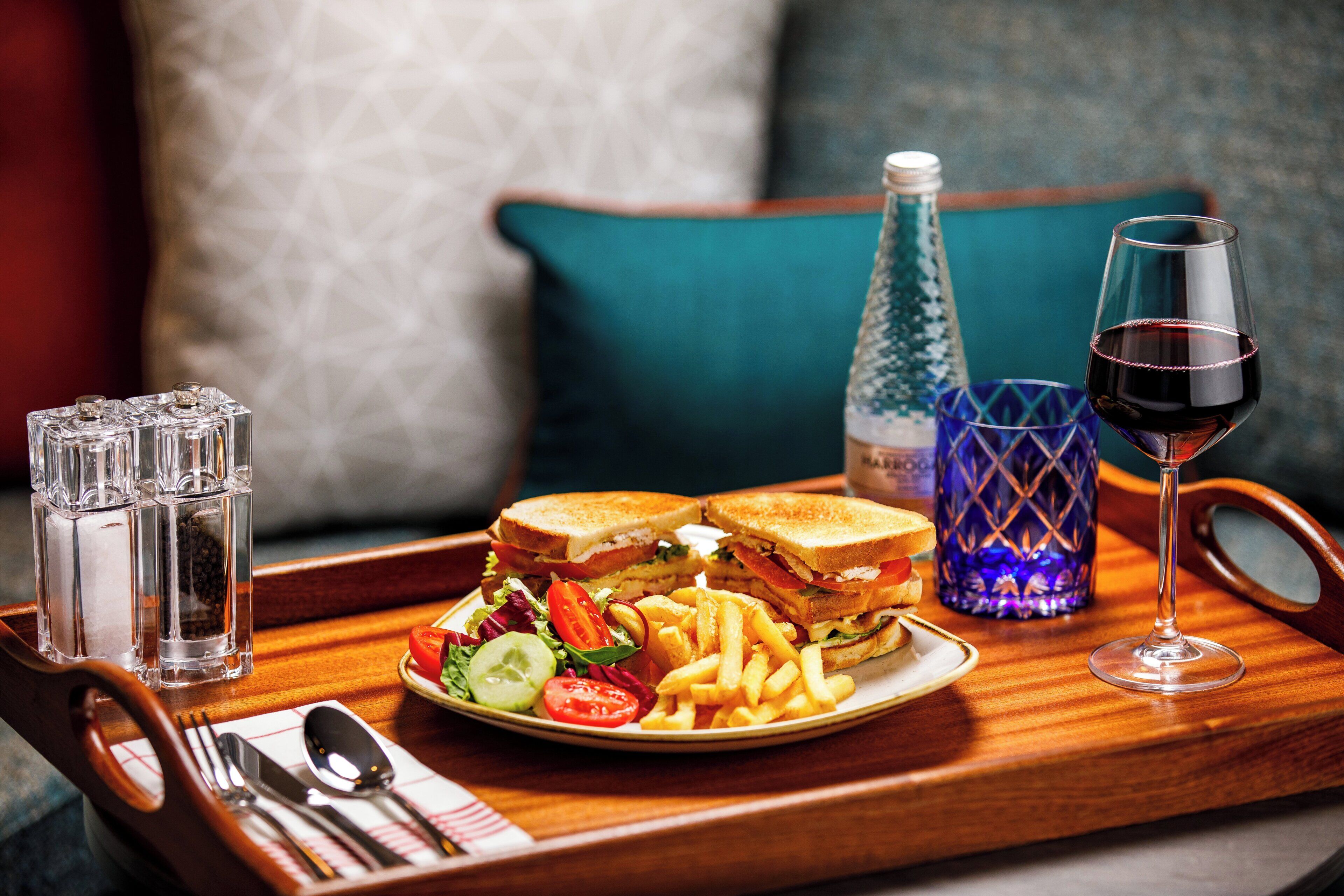 A tray with a sandwich, fries, salad, and a glass of red wine.