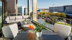A balcony with a sofa, chairs, a table, and a potted plant. - Holiday Inn Manchester Airport by IHG (Manchester)
