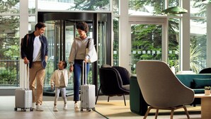 A modern hotel lobby with a glass elevator, comfortable seating, and a view of greenery outside. - Holiday Inn Manchester Airport by IHG (Manchester)