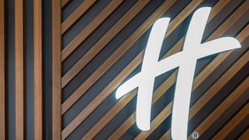 A wall with a geometric pattern and a large illuminated letter 'H'.