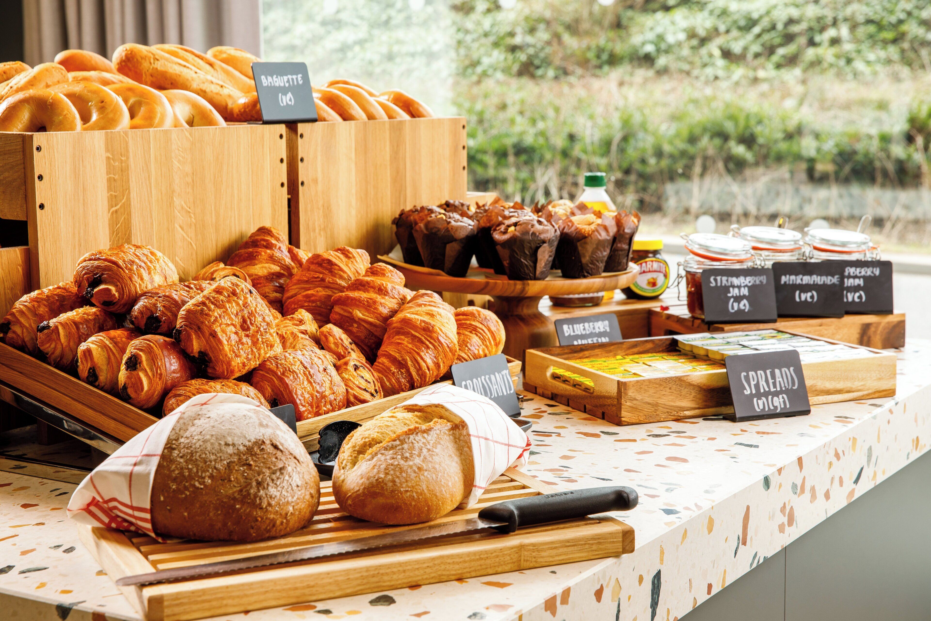 A bakery display with various baked goods and jars of spreads.