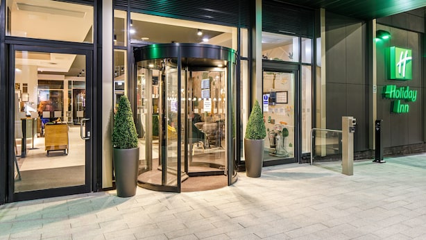 A hotel entrance with a revolving door, glass doors, and a Holiday Inn sign. - Holiday Inn Manchester Airport by IHG (Manchester)