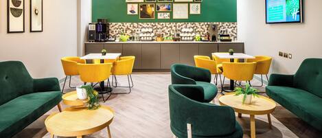 Un moderno vestíbulo de hotel con sofás verdes, sillas amarillas y una zona de bar central.