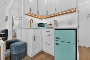 A compact kitchen with white cabinetry, a teal refrigerator, and a modern faucet. - Offer/PoolStepsToBeach/Dine/Zen Studio (Palm Beach)