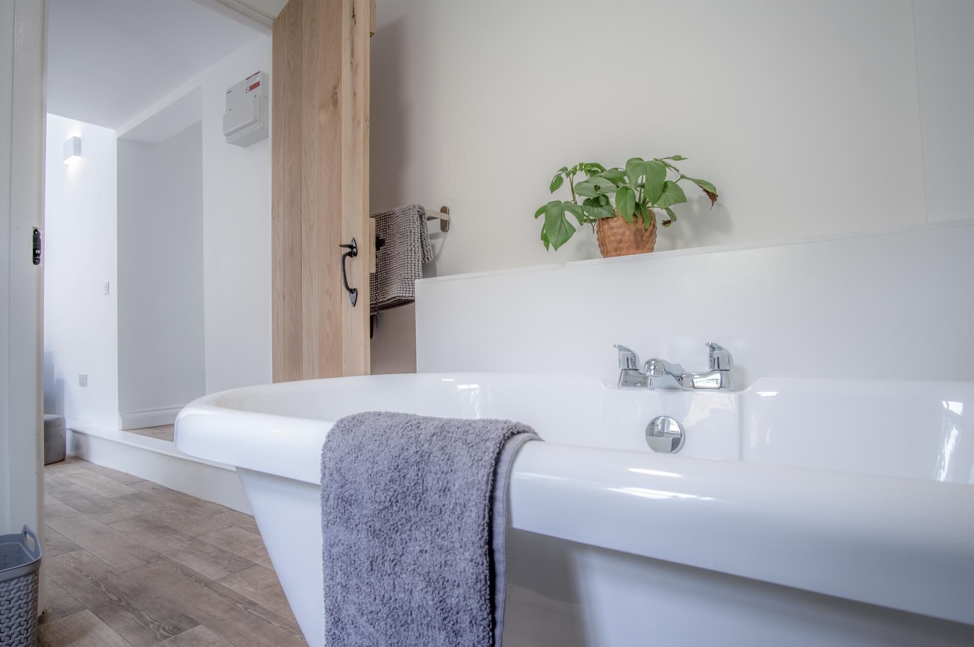 Ein modernes Badezimmer mit einer großen weißen Badewanne, einem Handtuch und einer Topfpflanze.