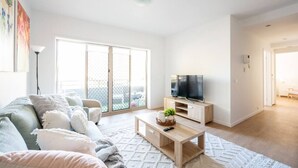 Un salon moderne avec un canapé, une table basse et un téléviseur.