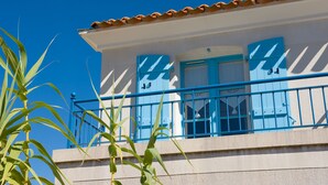 A building with a balcony, a blue door, and a tiled roof.